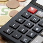 Calculadora junto a monedas y billetes de euros.