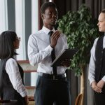 Un jefe de camareros de color habla con el resto del equipo de sala antes de abrir el restaurante