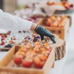Una mano con guante negro coloca los canapés de un catering correctamente
