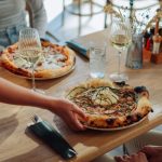 Una camarera coloca dos pizzas en la mesa de unos clientes