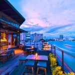 Bar en la terraza de un edificio alto con vistas a un río/mar/lago