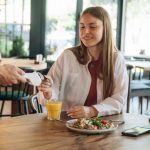Joven rubia pagando con tarjeta de crédito en el datáfono su cuenta en el restaurante